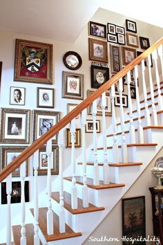 a staircase with pictures on the wall and framed photos on the wall above it in a home