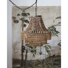 a chandelier hanging from a chain in front of a painting with palm trees