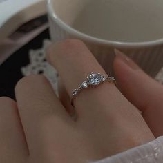 a woman's hand with a diamond ring on her finger next to a coffee cup