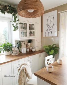 a kitchen filled with lots of white furniture and wooden counter top space next to a window