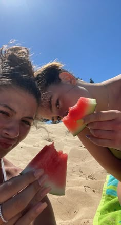 two women eating slices of watermelon on the beach