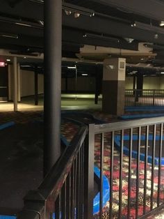 an empty parking garage filled with lots of blue and red carpeted area next to a metal railing