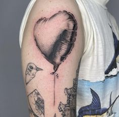 a man with a heart shaped balloon tattoo on his arm