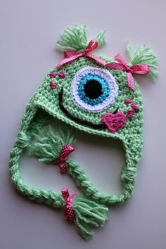 a crocheted hat with an eye and pink bow on it's brim