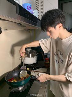 a young man is cooking on the stove with a pot and pan in front of him