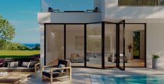 an outdoor living area with couches and tables next to a swimming pool in front of a house