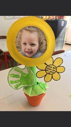 a child's handprint on a paper plate in a potted plant with a flower