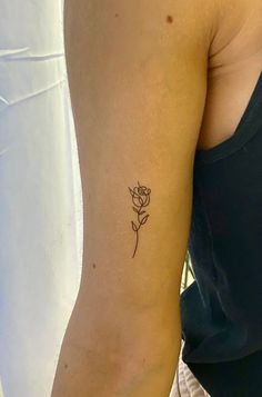 a woman's arm with a single rose tattoo on the left side of her arm