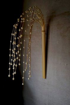 a wall mounted bamboo plant next to a wooden pole with beads hanging from it's side