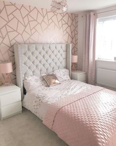 a bedroom with pink bedding and wallpaper in the corner, along with a chandelier