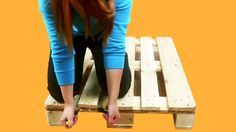 a woman sitting on top of a wooden pallet with her legs crossed and one leg bent