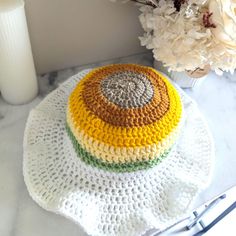 a crocheted dishcloth on a table next to a vase with white flowers