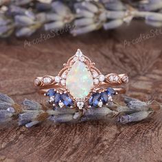 an opal and tan diamond ring with blue sapphires on the side, sitting on a piece of wood