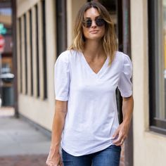 Introducing the Amaryllis Women's V-Neck Puff Sleeve Tee, where casual meets elegance. This tee features a flattering V-neckline that enhances the neckline, while the puff sleeves with gathered shoulder detail add a stylish and feminine touch. Made from soft stretch fabric, this tee provides comfort and ease of movement, making it an ideal choice for everyday wear. The relaxed fit ensures it pairs effortlessly with jeans or skirts for a versatile look. Whether you're running errands or meeting f Stretch V-neck T-shirt For Day Out, Casual V-neck Cotton Puff Sleeve Top, Feminine V-neck Tops With Relaxed Fit, White V-neck Puff Sleeve Top For Day Out, Chic V-neck T-shirt For Fall, Feminine Relaxed Fit V-neck Tops, Chic Fall V-neck T-shirt, White V-neck Top For Casual Gatherings, Chic Stretch V-neck Puff Sleeve Top