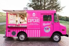 a pink truck parked on the side of a road with a woman standing behind it