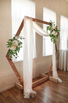 a wedding arch decorated with flowers and greenery on the floor in front of a window