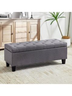 a gray bench sitting on top of a wooden floor next to a dresser and mirror