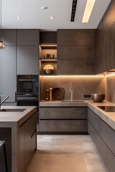 a modern kitchen with grey cabinets and marble counter tops is lit by recessed lighting