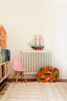 a room with a radiator, bookshelf, and chair in it