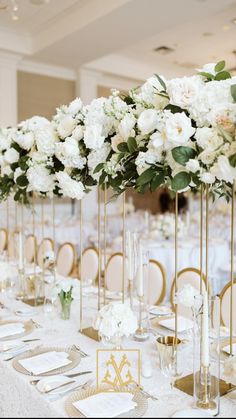 there are many tall vases with white flowers on the tables at this wedding reception