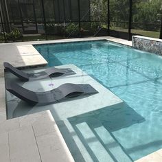 an empty swimming pool surrounded by glass walls and tiled flooring, with lounge chairs on the side