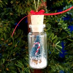 an ornament hanging from a christmas tree in a glass jar with candy canes