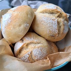 a bowl filled with rolls covered in powdered sugar and sitting on top of a table