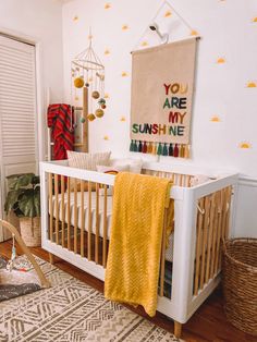 a white crib with a yellow blanket hanging on the wall