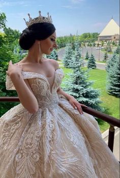 a woman in a ball gown with a tiara on her head looking out the window