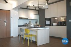 a kitchen with two yellow chairs next to a white counter top and wooden flooring