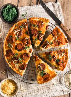 a pizza sitting on top of a wire rack next to a bowl of cheese and sauce