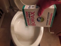 a person is cleaning the toilet with a soap and toothpaste box on it