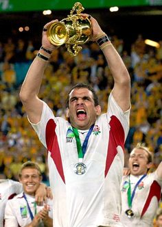 a man holding up a trophy in front of his face with other people behind him