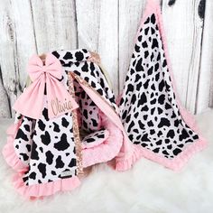 two baby blankets with pink bows and black and white cow print, one has a name on it