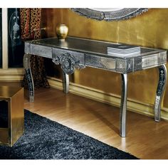 a silver table sitting on top of a hard wood floor next to a gold wall