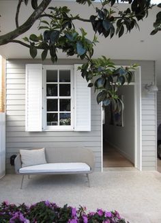 a white couch sitting under a tree next to a window