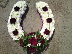 flowers arranged in the shape of the letter o on cement surface with white and red carnations