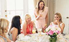 a group of women sitting around a table with food and drinks in front of them