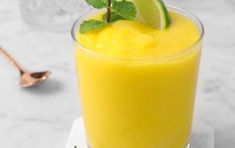 a glass filled with orange juice and garnished with mint leaves on a white plate