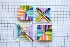 four small pieces of colorful fabric on top of a cutting mat with lines in the background