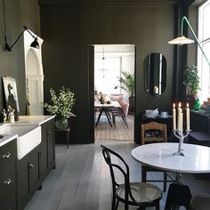 an open door leading to a dining room and kitchen area with black walls, white flooring and wooden floors