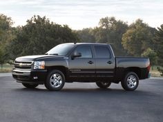 a black pickup truck parked in a parking lot with trees in the backgroud