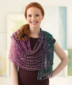 a woman wearing a crocheted shawl with her hands on her hips smiling at the camera