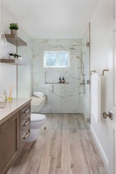 a bathroom with white walls and wood flooring, along with a walk in shower