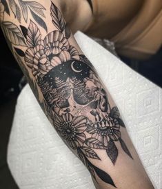 a person with a tattoo on their arm that has a skull and flowers on it