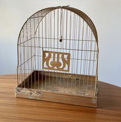 a birdcage with a cut out of the word jesus on it sitting on a wooden table