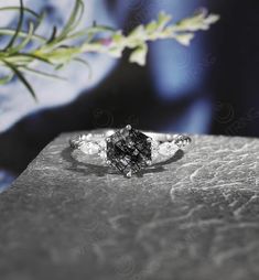 a black and white diamond ring sitting on top of a table next to a plant