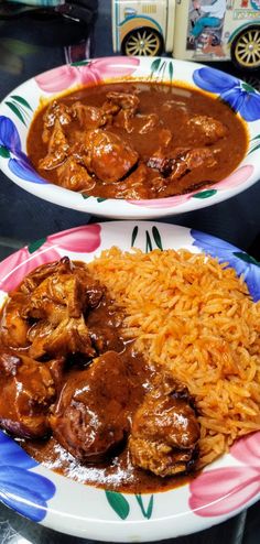 two plates filled with rice and meat covered in gravy on top of a table