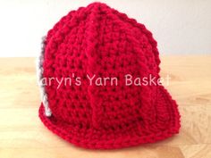 a red crocheted hat sitting on top of a wooden table