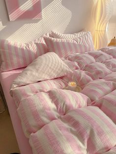 a pink and white striped comforter on a bed